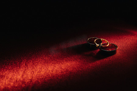 红色背景上的两枚结婚戒指和一枚订婚戒指。