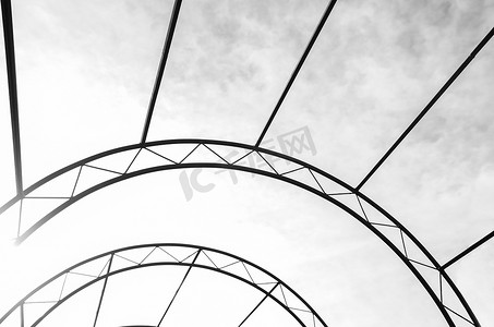 钢结构背景摄影照片_在天空背景抽象的弧形金属结构。