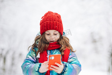 快乐的小孩使用智能手机有趣的面罩应用程序看着手机屏幕对一些有趣的事情微笑。