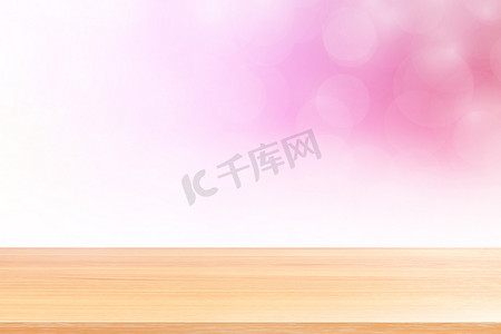 粉红渐变摄影照片_空木桌地板在模糊的散景柔和的粉红色白色渐变背景上，木板空在粉红色散景彩色浅色阴影上，彩色散景灯渐变柔和，用于横幅广告产品