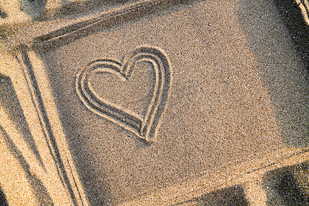 手绘旅游摄影照片_在框架中的沙子上绘制的心，特写。