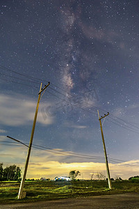 夜间乡村的电线杆，满天繁星和美丽的芋头场景，草地上方地平线下的云彩