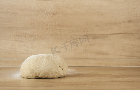 木制背景上的披萨面团球，撒上面粉