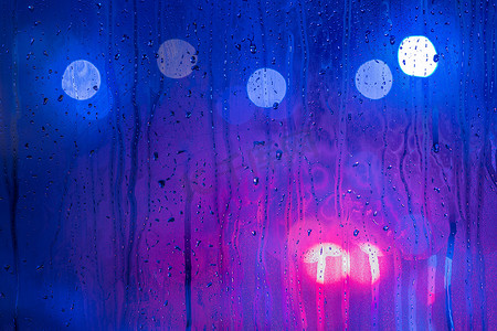 红色、紫色和蓝色夜路灯的抽象背景散景槽湿玻璃，有选择的焦点