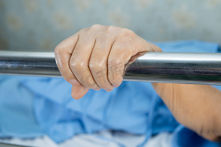 扶老人摄影照片_亚洲老年或老年老年妇女病人躺在医院的床上，满怀希望地扶着栏杆床。