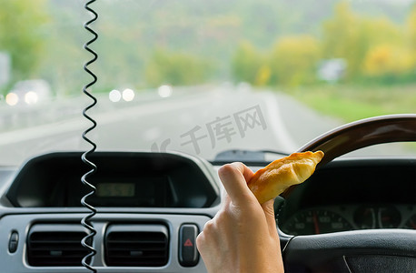 特写镜头，女手在高速公路上行驶的汽车方向盘后面握着一个发髻