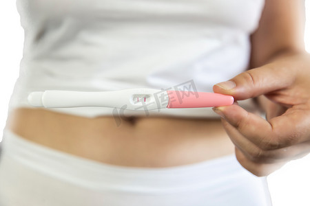 年轻女性穿着白色内衣，手握妊娠试验阳性结果和腹部。