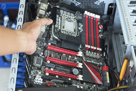 芯片组摄影照片_将带有 CPU 的主板带电缆手动放入 ATX 电脑机箱中