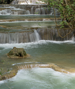 水在自然界的循环摄影照片_那里干净的瀑布呈翠绿色，这是由树木和地衣在黄色石灰岩中循环的反射造成的。