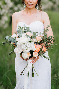 白色的裙子摄影照片_新娘穿着白色的裙子，拿着一大束春天的花束