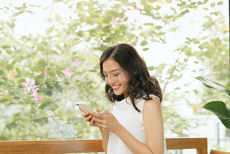 商务自由亚洲女性坐在咖啡馆的桌子上使用智能手机聊天、阅读和发短信。