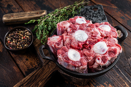 生小牛肉牛肉牛尾肉在屠夫木板上用切肉刀。