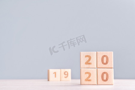 2023兔年来了摄影照片_摘要 2020 年和 2019 年新年倒计时设计理念 — 木桌上的木块立方体和低饱和度蓝色背景，特写，复制空间。