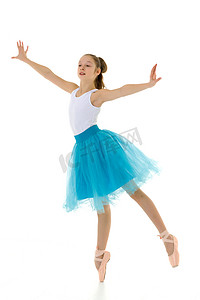 穿着芭蕾舞短裙和足尖鞋的可爱小女孩在白色背景的工作室里跳舞。