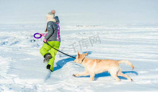 带着狗在雪地里奔跑的女孩