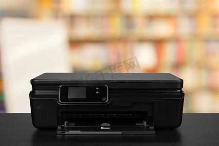 背景模糊的黑色办公桌上的紧凑型激光打印机