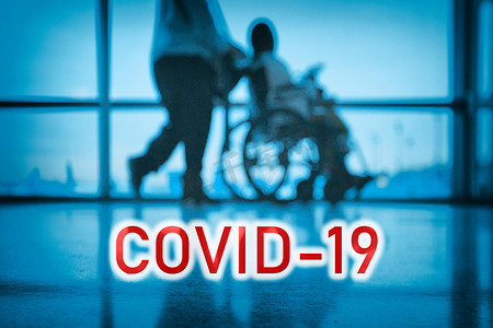 蓝色医疗医院背景上的COVID-19广告牌红色文字，医生与轮椅上的残疾患者同行