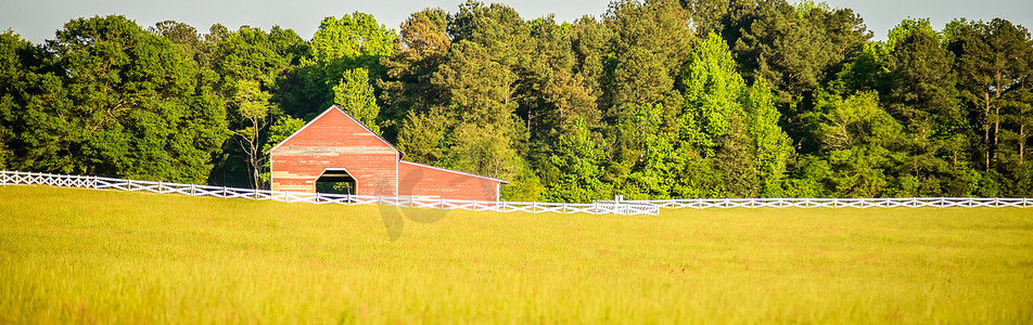 白色的栅栏通向一个红色的大谷仓