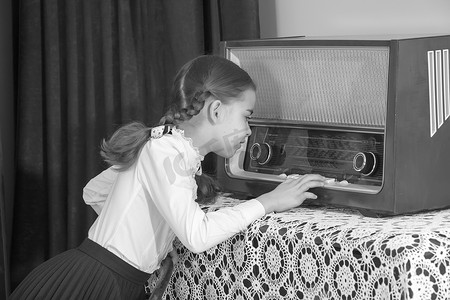 小女孩听旧收音机。