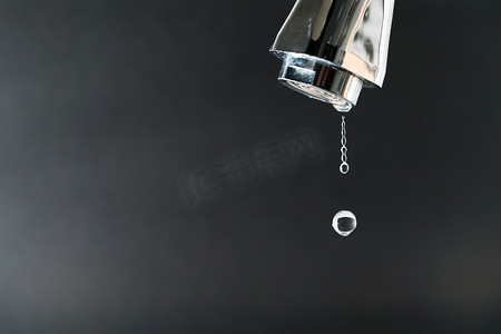 水龙头黑色摄影照片_黑色背景水龙头上的水滴，世界水日公司
