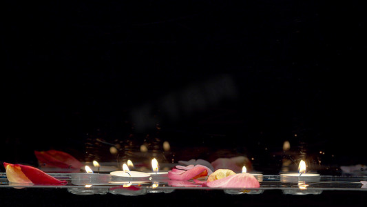 漂浮在水面上的蜡烛和飘落的玫瑰花瓣
