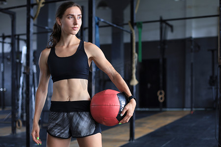 肌肉发达的女强人在运动量来找到健身房携带药球。