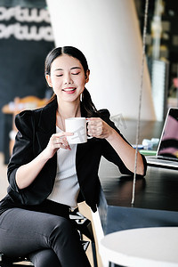 一位女营销经理正在喝杯咖啡休息，然后返回工作岗位以减少睡意。