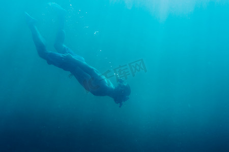深海蜜柚摄影照片_年轻人自由潜水员在深海中游泳。