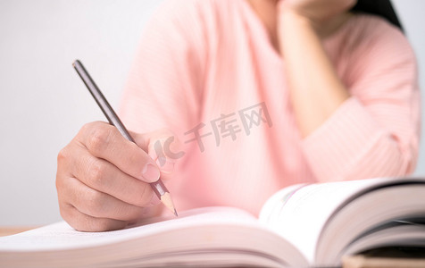 女人在图书馆读书时画线并写简短摘要的特写。