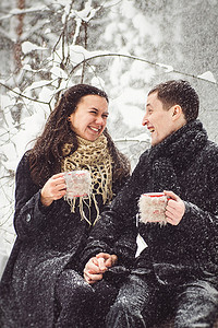 一个穿着暖和的衣服和围巾的男孩和女孩在雪天散步