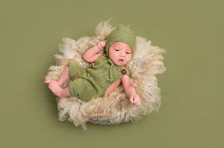 婴儿毛毯摄影照片_穿着针织服装的婴儿，滑稽的姿势