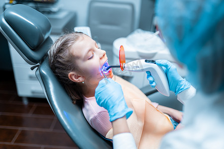 为小女孩提供牙齿修复和固化聚合紫外线灯填充的牙医