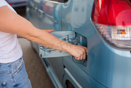 妇女在自助加油站用汽油给汽车加油。