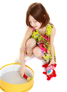 小女孩在玩一个圆盒子。