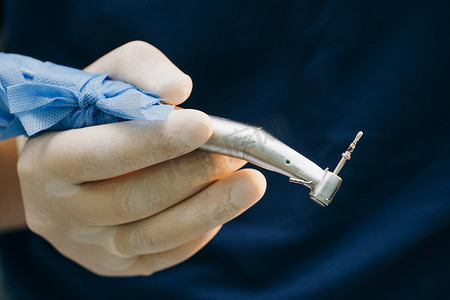 牙医的手戴着手套在牙科诊所用牙钻工作。