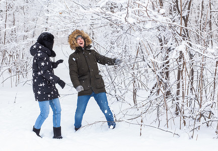 恋爱中的年轻情侣在白雪皑皑的森林里玩得开心。