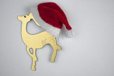 白色背景中的圣诞金玩具鹿和圣诞老人​​帽