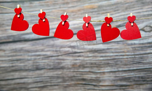情人节、母亲节、妇女节的爱情概念，木制背景上挂着红色的红心，浪漫的设计复制空间