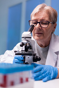 白大衣高级化学研究员在高端显微镜下寻找疾病专业知识