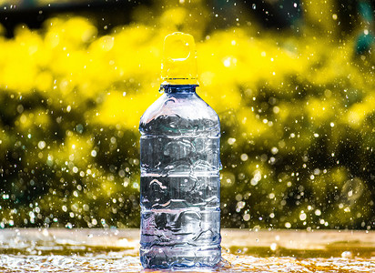 纯净水摄影照片_新鲜纯净水溅在瓶子周围，背景模糊。