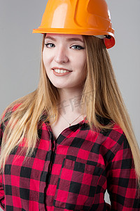 一个年轻漂亮的女人的画像，金发在中性灰色背景上的橙色头盔。