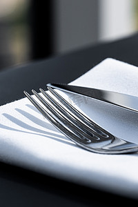 户外豪华餐厅的桌上放着白色餐巾的叉子和刀子，婚礼或活动的精美菜单以及餐饮服务理念
