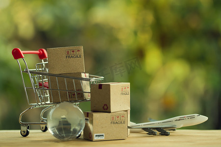 网上购物和电子商务概念：购物车中的纸盒和水晶球、飞机。