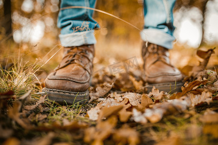 男人的腿走在秋叶上