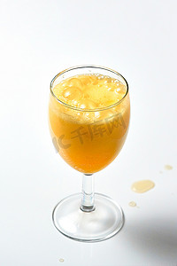 玻璃高脚杯与白色背景上冒泡的橙色液体。