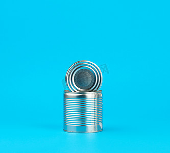 铁罐可口可乐摄影照片_打开蓝色背景下保存食品的硬铁罐，