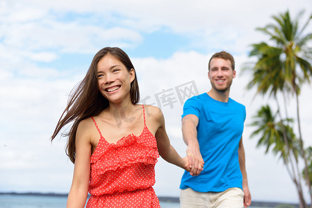 快乐的暑假情侣牵着手在海滩旅游目的地散步。