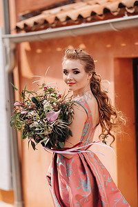 一个年轻的模特女孩穿着漂亮的裙子，在法国乡村拿着一束鲜花。