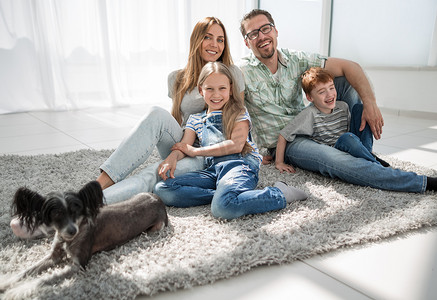 地毯摄影照片_有宠物的幸福家庭坐在地毯上