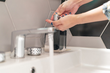 卫生间细菌摄影照片_妇女在卫生间用液体肥皂洗手
